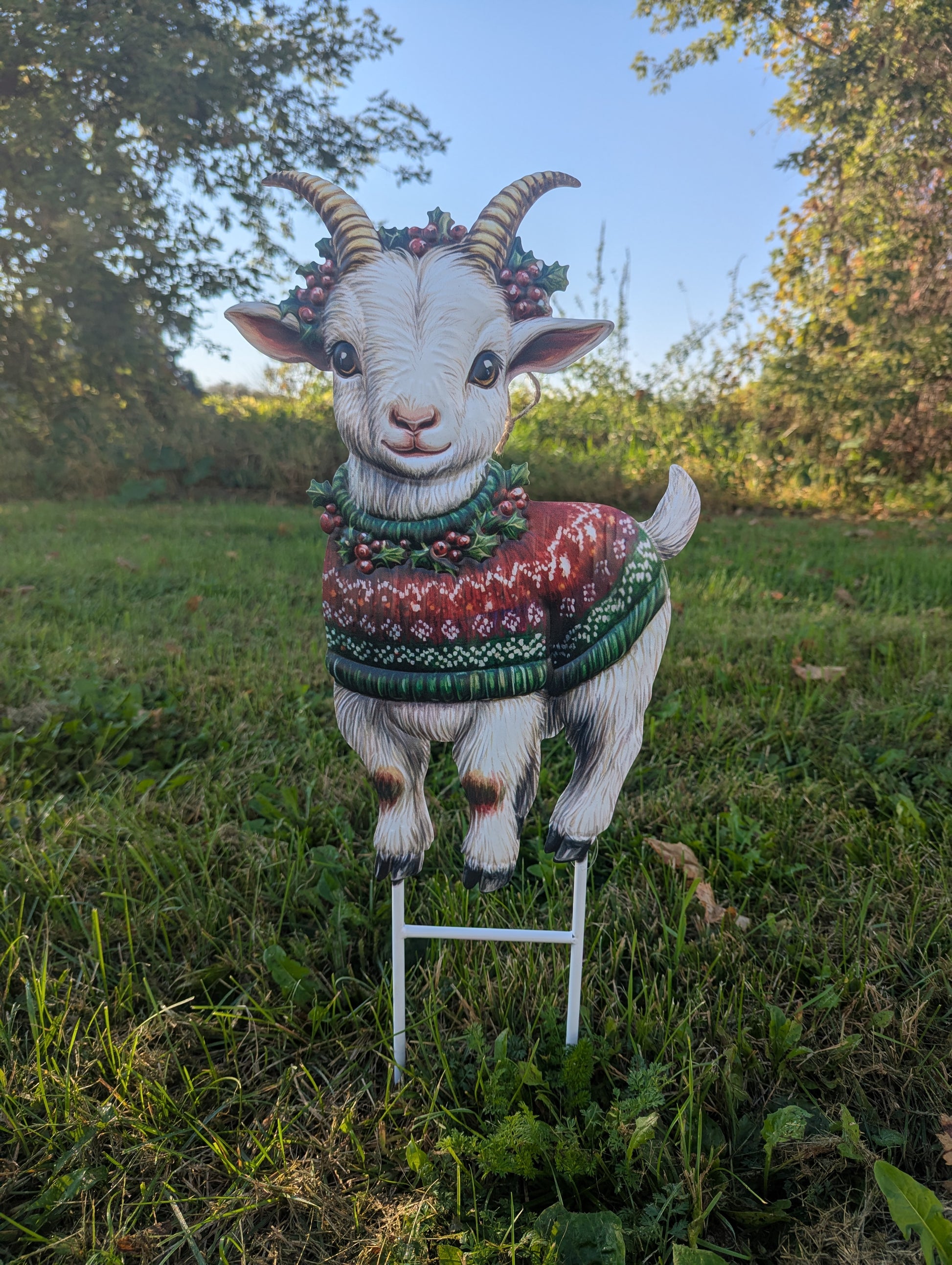 Decorative goat figurine wearing a sweater on a grassy lawn